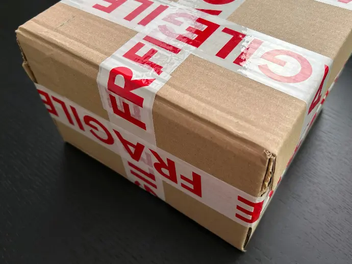 Cardboard box sealed with red fragile tape